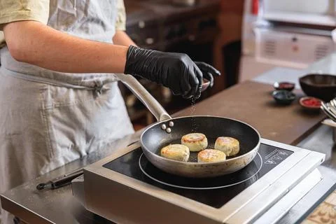 Professional Chef preparing cheesecakes on frying pan for breakfast in Foto stock