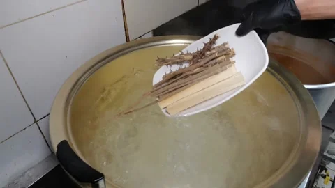 Professional chef preparing chicken soup with herbs in a large metal pot Stock Footage 345510354
