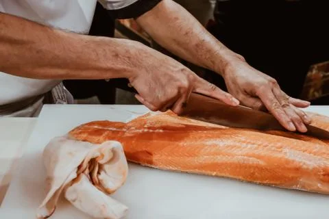 Professional chef preparing a fresh salmon on a cutting board. Stock Photos