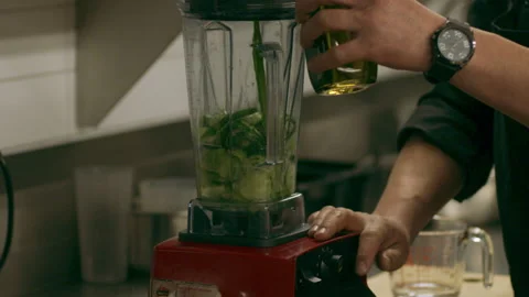 Professional chef putting oil into a blender with cucumber in industrial kitchen Stock Footage 199459158