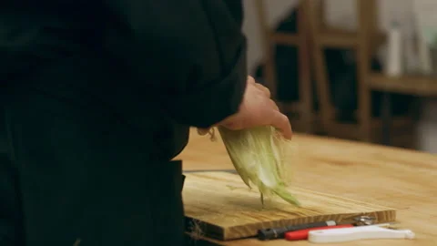 Professional chef removing ears of corn and placing sliced tomatoes onto wooden Stock Footage 199458923