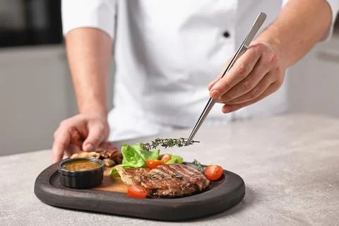 Professional chef serving dish at table indoors, closeup Stock Photos