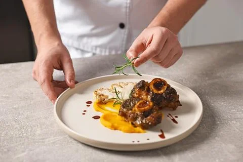 Professional chef serving dish at table indoors, closeup Stock Photos