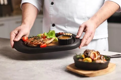 Professional chef serving dish at table indoors, closeup Stock Photos