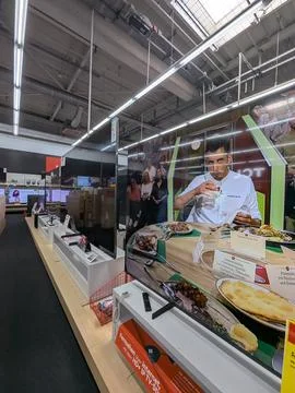 Professional chef serving food in electronics store display side view with chef. 写真素材