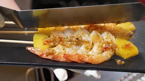 Professional Chef Serving Gourmet Grilled Seafood and Fruit Skewers on a Black P Stock Footage 337440686