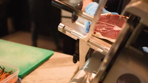 Professional Chef Slicing Cured Ham with Electric Meat Slicer Stock Footage 338427545