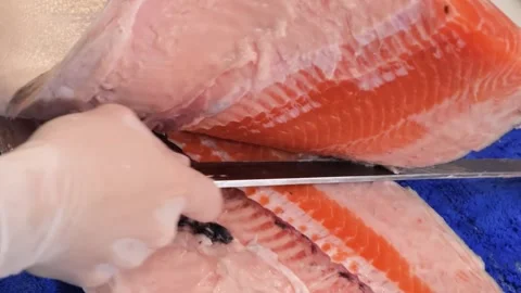 Professional chef slicing fresh raw sockeye salmon fillet with precision on a cu Stock Footage 333489058