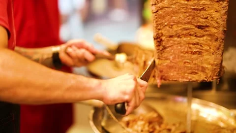 Professional chef slicing meat from a vertical rotisserie for traditional t.. 스톡 동영상 332840337