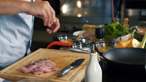 Professional chef in spacious kitchen prepares meat, salt, abundantly pour oil Stock Footage 123352956