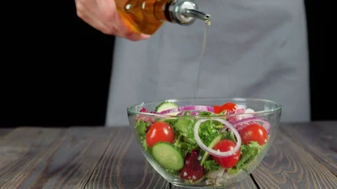 Professional chef sprinkles a ready-made summer salad with olive oil Stock Footage 129746675