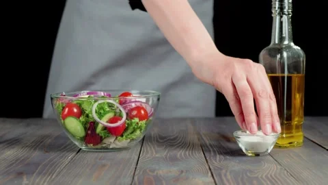 Professional chef sprinkles a ready-made summer salad with sea salt Stock Footage 130516179
