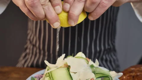 Professional chef squeezes lemon juice on green salad. Healthy eating concept. Stock Footage 302586083