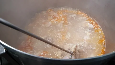 Professional chef stirring a pot of simmering soup in a busy kitchen Stock Footage 278532138