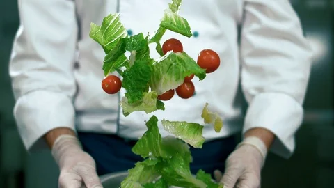 Professional chef throws salad in an iron bowl. Slow motion shot Stock Footage 102661056