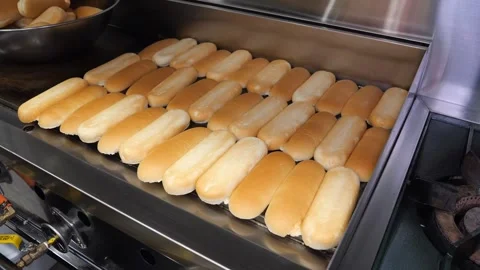 Professional chef toasting buttered hot dog buns on a large commercial flat gril Stock Footage 324710959