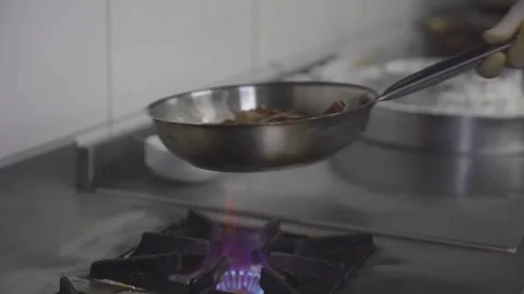 Professional chef tossing meat in pan over gas stove flame, Izmir 2023 Stock Footage 332116360