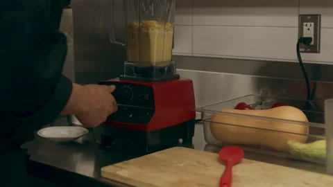 Professional chef turning on blender to puree orange vegetables and corn in indu Stock Footage 199457948
