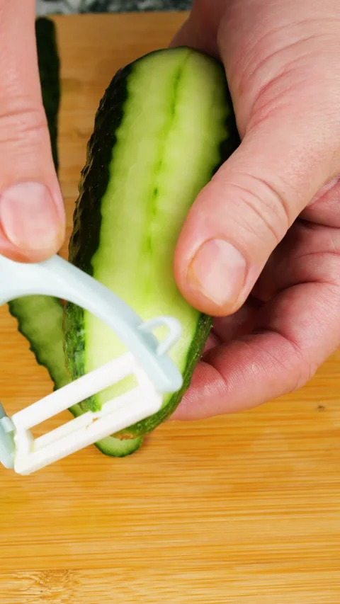 A professional chef uses a white peeler to remove the green skin. Stock Footage 341542071