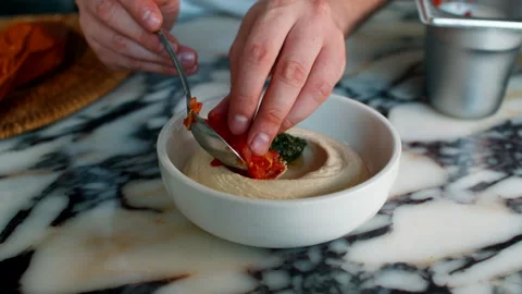Professional chef using a spoon to carefully add a tomato and pepper garnish Stock Footage 337183149