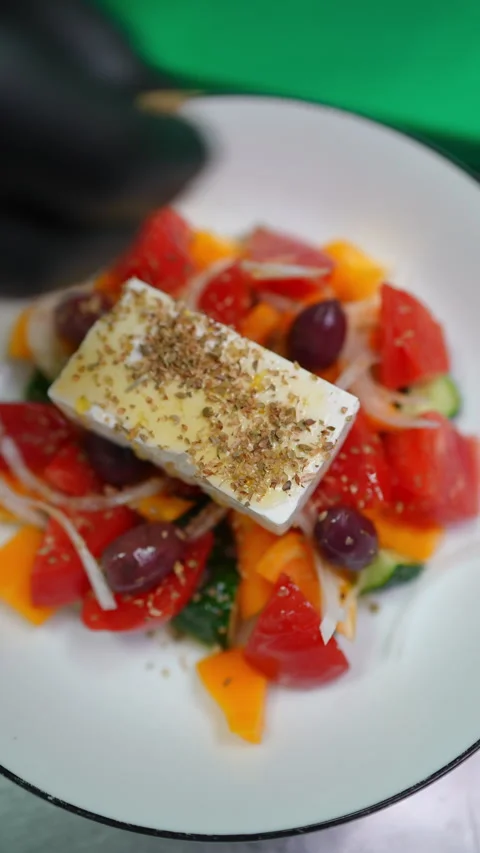 Professional chef wearing protective gloves seasoning vibrant greek salad with Stock Footage 309140833