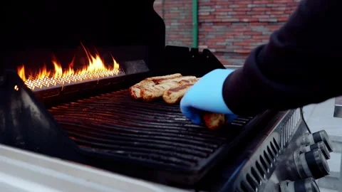 Professional chef wearing protective gloves grilling sausages, flames dancing Stock Footage 331464129