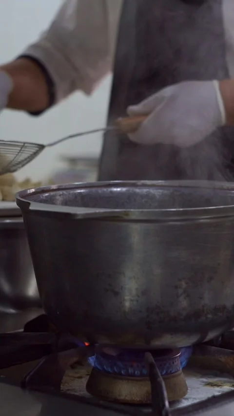 Professional chef in white gloves using a wire skimmer to take boiled dumplings  Stock Footage 342345274