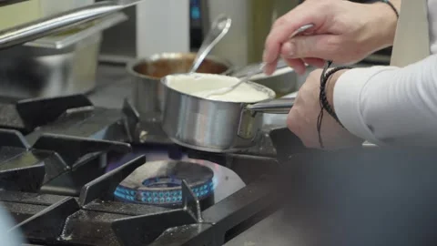 Professional chef working in a commercial kitchen preparing a meal with steam ri Stock Footage 308590365