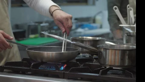 Professional chef working in a commercial kitchen preparing a meal with steam ri Stock Footage 310956154