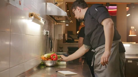 Professional Chef Writing Recipe Notes at Workstation in Restaurant Kitchen Видео 330061733