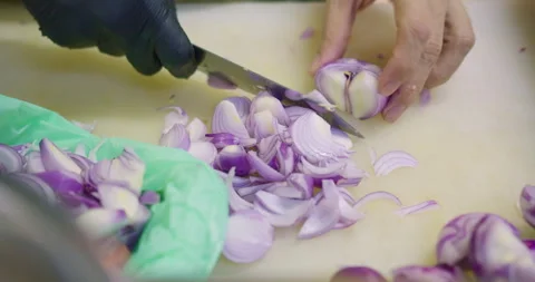 Professional chef's hands skillfully slice fresh red onions on a cutting board Stock Footage 339540490