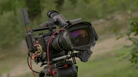 Professional cinema camera set up at grassy meadow Stock-Footage 303071441