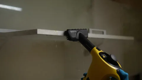 Professional cleaner in gloves using handheld steam cleaner to eliminate grease Stock Footage 293512250