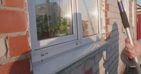 Professional cleaner or homeowner using a long-handled squeegee tool to wash the Stock-Footage 324819011