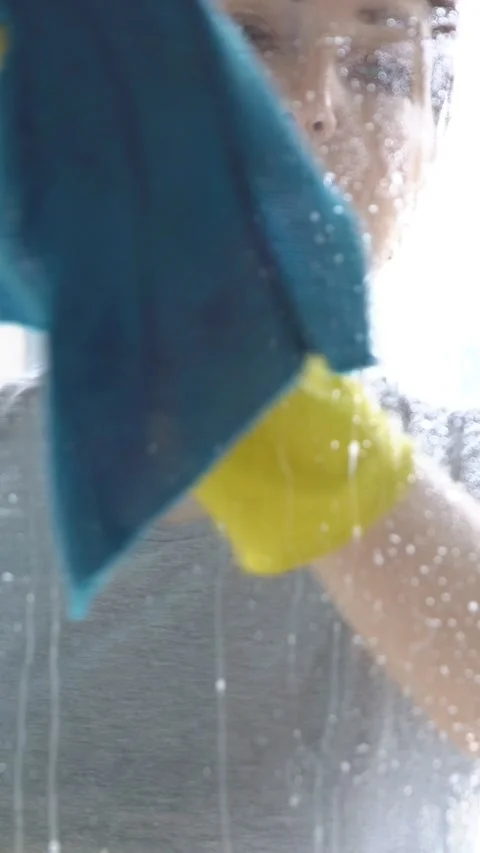 Professional cleaner wiping a sprayed window with a cloth for cleaning, washing Stock Footage 344812907