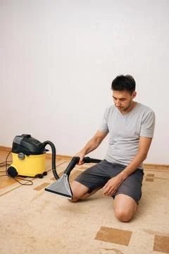 Professional cleaning service worker using washing vacuum cleaner to remove dirt Stock Photos