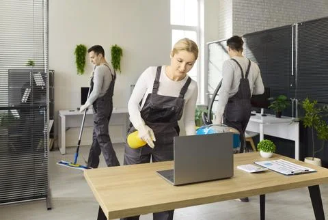Professional cleaning team servicing modern office workspace with hygiene focus Stock Photos