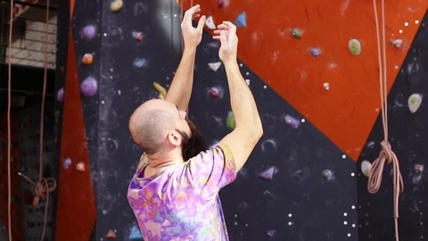 Professional climber plans his next route on climbing wall. Video 1080p Stock Footage 77803952