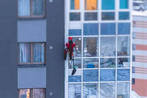 Professional climber rope access worker with a shovel removes snow and take o Stock Photos