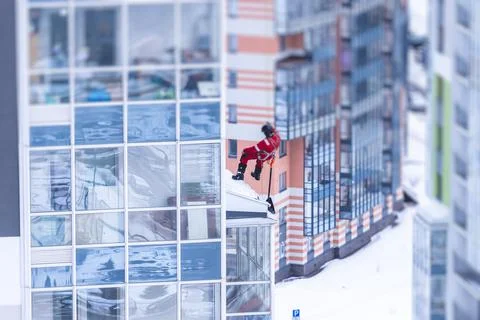 Professional climber rope access worker with a shovel removes snow and take o Stock Photos