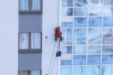 Professional climber rope access worker with a shovel removes snow and take o Stock Photos