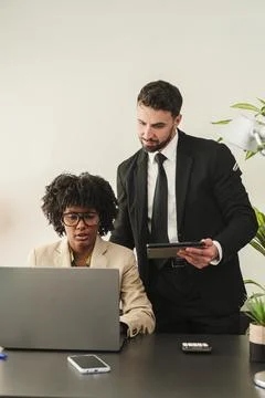 Professional colleagues collaborating on a laptop while reviewing important Stock Photos