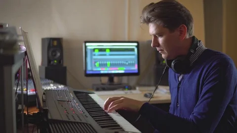 A professional composer composes music on an electronic piano in the Studio Stock Footage 72435406