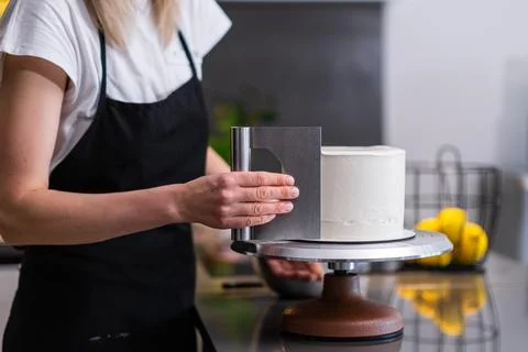 Professional confectioner using pastry scraper to handle white mastic on baked Photos