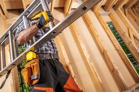 Professional Construction Site Worker Moving Ladder Inside a House Stockfoto's