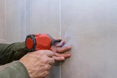 Professional construction tools in handyman working with drill tile in bathro Stock Photos