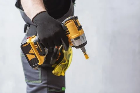 Professional construction worker in gloves holding powerful cordless impact.. Stock Photos