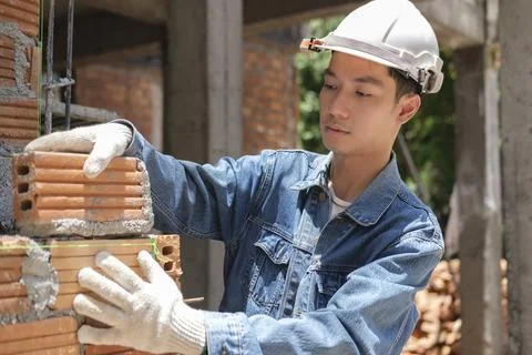 Professional construction worker installing bricks on construction site Stock Photos