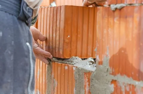 Professional construction worker laying clay bricks blocks and building wall  Stock Photos