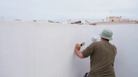 Professional construction worker painting white rooftop wall with roller du.. Stock Footage 334549424